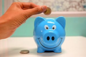 Blue piggy bank with coin being deposited.